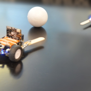 To robotbiler som kjemper om en ball.