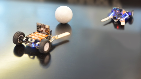 To robotbiler som kjemper om en ball.